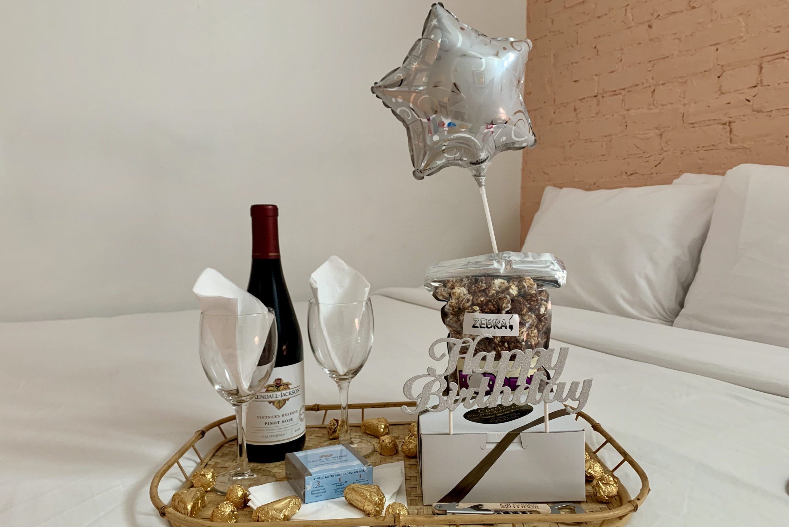 Popped popcorn, wine, and Cassis chocolates on bed